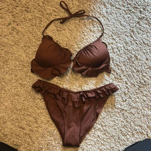 Brun bikini hm - Supersnygg brun bikini med volang från hm! Trosorna är i storlek 36 och toppen i storlek 38🤎