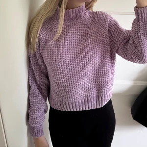 Ljuslila stickad polotröja - Supermysig ljuslila stickad polotröja med grov struktur och ribbade muddar. Tröjan har en hög krage och långärmade ärmar, perfekt för att hålla värmen under kyliga dagar. Storlek S men passar XS 