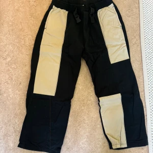 District Fortysix cargopants svart/beige L - Snygga cargopants från District Fortysix i svart med breda beige paneler framtill. Byxorna har loose fit