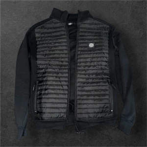 Svart cardigan jacka Stone Island M - Svart quiltad jacka från Stone Island i storlek M. Jackan har ribbade muddar, dragkedja framtill och två sidofickor med dragkedja. Passar perfekt för vår, och mild vinter. Ett till ett kvalité 