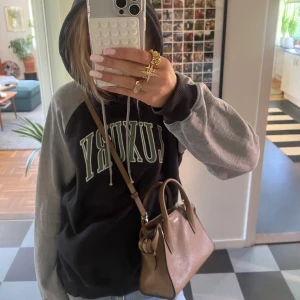 Svart och grå hoodie från VAILENT  - Säljer en svart hoodie med grå ärmar och huva. På bröstet står det 'LUXURY' i stora gröna bokstäver med vit kant. Tröjan har snörning i huvan och ribbade muddar. Storlek M💋💋