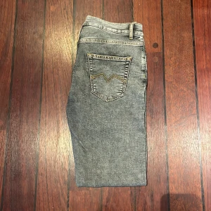 Grå jeans från Montén, rak modell - Säljer ett par grå jeans från Montén i rak modell. Jeansen har klassisk femficksdesign, snygga kontrastsömmar och en cool tvättad look. Passar dig som gillar en enkel men stilren vibe.