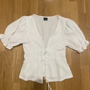 Vit blus - Säljer denna superfina vita blusen från Gina med knytdetaljer fram. Den är använd ca 5 gånger och har inga defekter. Storlek xxs men sitter jättebra på mig som brukar ha S. För fler bilder eller frågor kom privat🩷