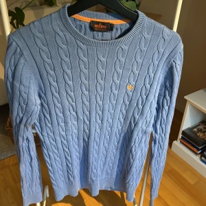 Flätad snygg tröja  - Bomullströja med flätat mönster, mellanblå (himmelsblå), använd ett fåtal gånger, mycket fint skick. 