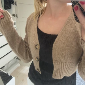Stickad kofta - Gullig stickad kofta i fin beige färg. Lite croppad i modellen och passar såå fint till många outfits!   Nyskick då den endast provats.