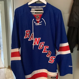 New York Rangers Hockeytröja - Hockeytröja från Reebook i storlek M/M. Använd 2-3 gånger och är i fint skick.