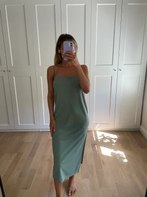 Grön klänning - Grön och väldigt skön klänning från HM. Har en slits längst höger ben och justerbara axelband. Tyget är dubbelt på över bysten. Sparsamt använd och inga anmärkningar. 💚 Storlek S 