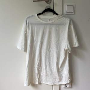 En vit T-shirt med ett stort tryck på baksidan, stryks självklart innan utskick 