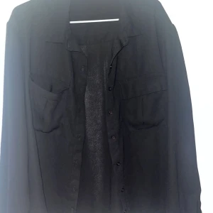 Skjorta Svart - Vardaglig svart skjorta från Bikbok. Superfin att både klä upp och ner. Långa armar med knapp vid handleden. Knappar hela vägen upp till halsen. 