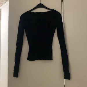 Tröja  - En lång armad svart tröja, sitter tajt på kroppen 