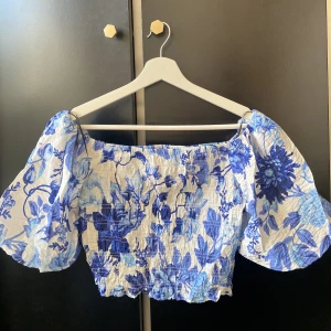 Blommig top - En blommig croppad top med puffiga ärmar ifrån h&m. Aldrig använd. Storlek S