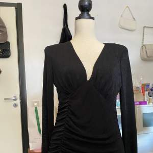 Glittrig svart fest/aftonklänning med snygg rouching på sidan och slit. Aldrig använd och i helt nytt skick