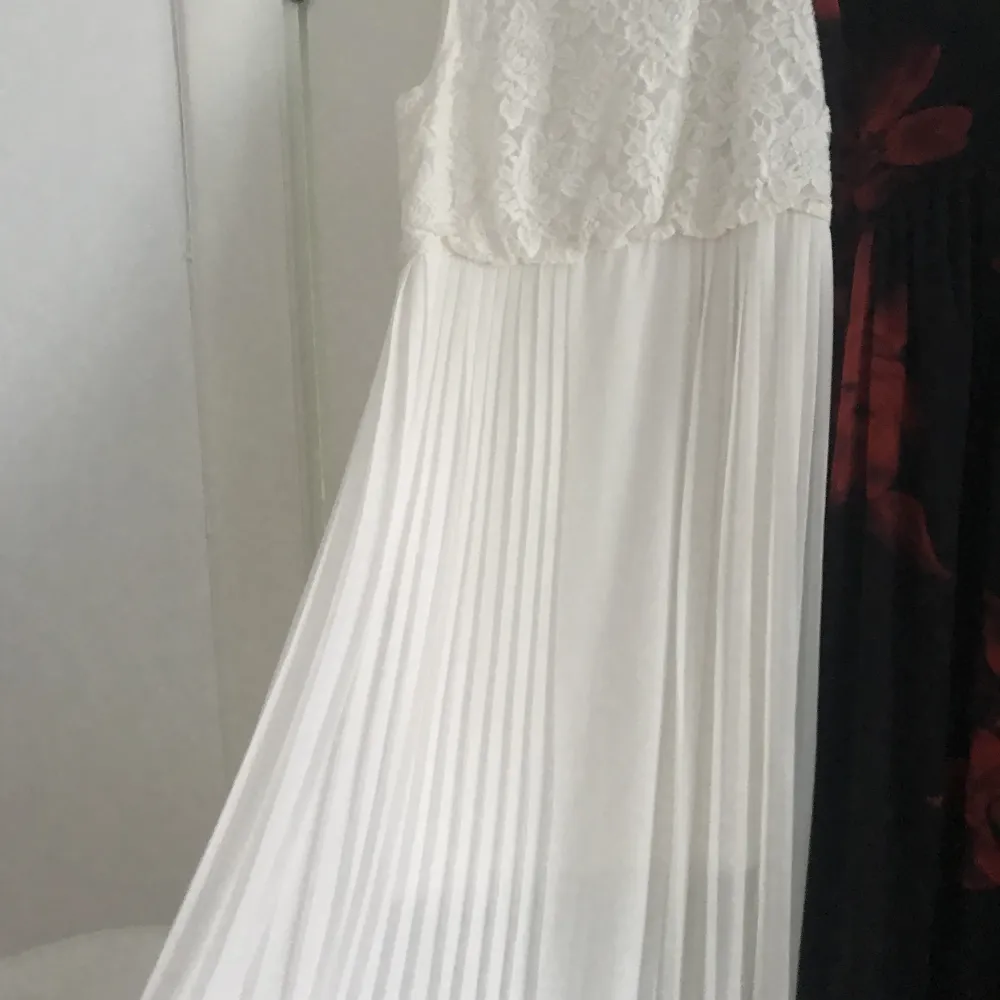Vit långklänning  Säljer denna söta klänning som bara hänger  oanvänd här! Underbar plisserad kjol med vita blommor i mönstret upptill ♥️ storlek 38 ♥️ passar till fest men funkar nog till bröllop också ♥️😍🥰. Klänningar.