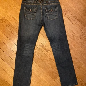 Jeans - Säljer dessa jeans då jag inte använder dem.   Coolt spänne och knappar på bakfickorna.  Storlek 38 EU.