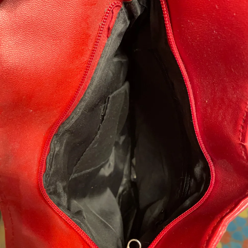 Röd väska med fina detaljer och långa axelband . Väskor.
