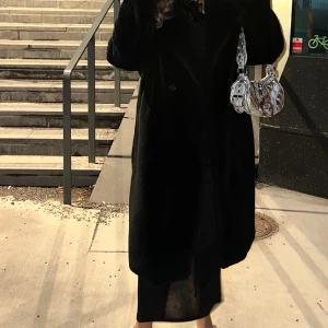 H&M fluffig kappa - Knälång, svart kappa i fakepäls.