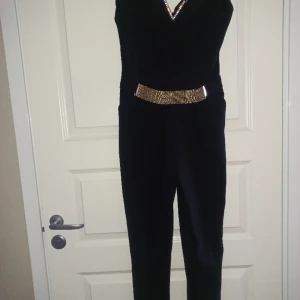elegant svart jumpsuit med guldtillbehör. - elegant svart jumpsuit med guldtillbehör, höjd 166/170.str.36/38. Pris 200kr. Mobil 0793537427. Välkommen 