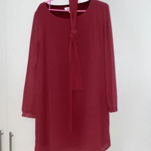 Röd långärmad kortklänning  - En vinröd och vacker klänning i meshliknande material. Använd under en julafton så kan vara passande till ett sådant tillfälle!🧑🏼‍🎄