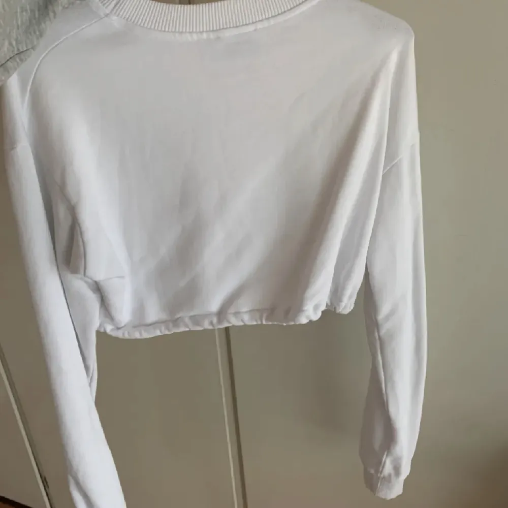Fin vit långärmad croppad tröja från NAKD. Resårband som kan spännas åt beroende på hur tajt man vill ha i midjan! . Tröjor & Koftor.