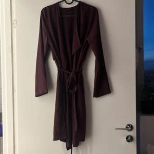 Tunika XS  - Tunika/längre tunn kofta i blusmaterial. Skärp i midjan  Lila/vinröd  Ginatricot  Storlek: XS/34  Använd men fint skick!! 