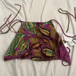 Backless topp med mönster - Lila topp med bladmönster från Zara!💗Helt oanvänd med lappen kvar! Toppen är i linnematerial och har ingen rygg, utan man knyter den på ryggen! Supersnyggt och härligt när det är varmt☀️Strl S men för den är så pass justerbar så kan nog XS & M också ha den