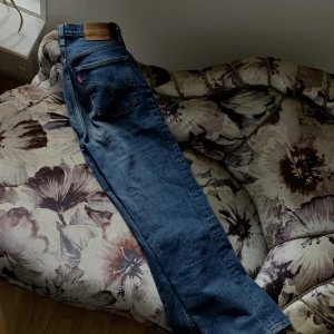 Levis Ribcage 25/27 - Säljer mina fina mörkblåa Levis i strl w25 l27. Jeansen är högmidjade och sitter så snyggt på. På mig som är 160 cm lång slutar jeansen vid fotknölen ungefär. De är använda men i bra skick. Nypris är ca 1200 kr. Säljer för 400 kr + frakt.
