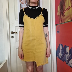 Gul klänning - Gul slip on-klänning i jeanstyg, med fransiga kanter. Jättesöt att ha över en tshirt eller en skjorta. Står ingen storlek, men skulle säga S. (Den svartvita tröjan finns också till salu i en annan annons)