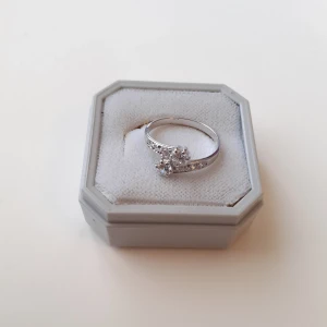 Silverring med stenar - Ring i äkta silver med gravering och 8 stenar. Ringen har en fin omlottdetalj, är i nyskick och helt oanvänd.  Storlek: 44 (Diametern är 1,5 cm) Ask: 10kr (valfritt) Frakt 15kr 