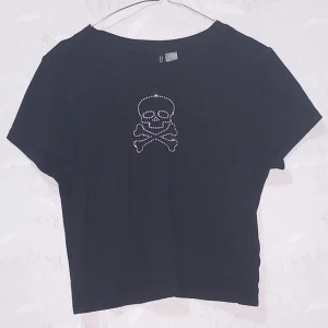 Crop top med dödskalle - Fin svart croptop med dödskalle från H&M rätt så tight vid bysten men lite halvlös vid magen