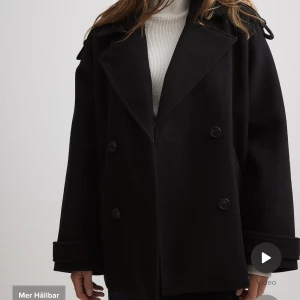 Så fin kort kappa - Jättefin kort svart kappa med fina detaljer från NA-KD. Endast använd några få gånger så den är i mycket bra skick, säljer då den är lite för stor för mig!! Skriv för egna bilder