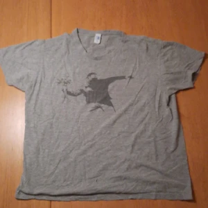 T-shirt - En grå t-shirt med mörk grå tryck. 85% bomull. Den är sjukt snygg men tyvärr inte passar mig lika bra längre.