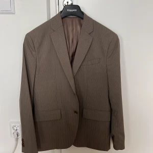 Stilig randig brun kavaj  - Stilig randig brun kavaj från Mango Men. Strl 50 - slimfit  Använd några gånger men i fint skick. 