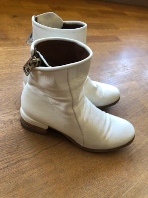 Vita läder stövlett  - A.S 98/Airstep vita läder stövlett med dragkedja snett, 4 cm klack. Några märken insida hälområdet gör att det syns att de är använda,  i övrigt hela, inte sneda, knappt slitna på sulan. Relativt breda över fotbladet 