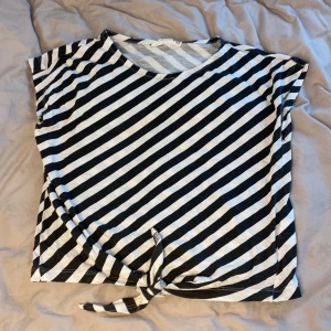 Svart vit randig t-shirt med knut - T-shirt i ett bra skick med knut, randig och fin för sommaren.