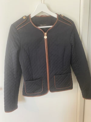Massimo Dutti Jacka strl S - Snygg svart quiltad höst/övergångs-jacka från märket Massimo Dutti i strl S.   Fint skick, använd endast 1 säsong. Har snygga gulddetaljer och är väldigt stilren.  Djur- och rökfritt hem.