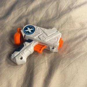 Liten X shot pistol leksak med skott - Du får med en X shot pistol och 6 skott , jag rekommenderar inte att man köper för att sjuta på någon annan då skotten flyger jättefort och kan göra ont.