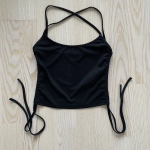 Svart linne med snörning - Ett svart croppat linne med snörning från Gina Tricot. Stl XS men sitter som XXS. Endast använd någon enstaka gång, säljer pga att den sitter för tight på mig som är XS. Djur- och rökfritt hem. ✨