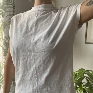 T-shirt/Linne - Vit t-shirt med korta ärmar. Snygg form, markerar axlarna! XS men oversized, passar även M. Tyvärr några små hål men annars i bra skick