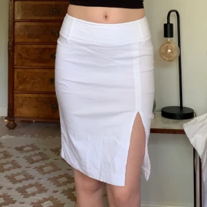 Vit kjol - Midikjol med slit framtill och dragkedja där bak, vintage Only! Midjemåttet är 70 cm (strechig) och längden 52 cm 🤍