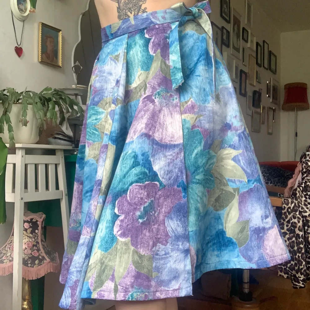 Handsydd vintage omlottkjol med lila och blåa blommor. Den är omlott med mycket tyg så man kan anpassa storleken mycket . Kjolar.