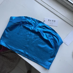 Blå festtop från NA-KD - Blå korsett top kräm NA-KD. Helt oanvänd, lappar är fortfarande kvar. Storlek L. Perfekt till sommaren. 