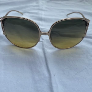 Solglasögon, Christian Roth - Solglasögon med tonat grönt glas och tunn guldram. Nyskick då de inte kommit till användning och medföljer rejält fodral inkl. Putsduk.