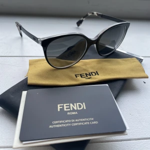 Fendi solglasögon med äkthetsintyg - Supersnygga svarta solglasögon från Fendi. Kommer med en pouch och duk att putsa med, samt äkthetsintyg. Köpta på NK 2015 (står på äkthetsintyget). 