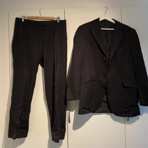 Tiger Of Sweden Kritstreckrandig svart kostym  - Hej, säljer en riktigt snygg svart kostym med vita linjer från Tiger Of Sweden. Den är i utmärkt skick med snygg passform. Storlek 50 vilket motsvarar en större medium/large. Nypris runt 5000kr. Priset är inte hugget i sten. Hör av dig vid intresse. 