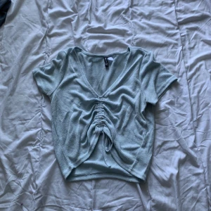 Ljusblå t-shirt med draggrej - Nypris 90 kr, använd 10-20 gånger. Inga fläckar eller hål finns på tröjan. Man kan ändra längd på tröjan där framme. 