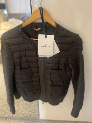 MONCLER CARDIGAN - Säljer min cardigan i nyskick. Köpt på Jackie, inga defekter alls. QR kod finns och lapp kvar. Snabba köp prioriteras. Byte mot liknande k storlek M är också av intresse❤️