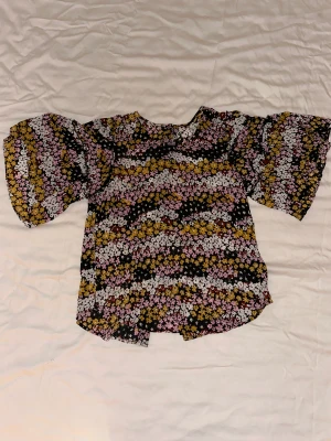 Blommig blus - Fin blommig blus i krusigt viscose-tyg 🌸〰️🌼En sida har knappar hela vägen ner, så den går att använda som skjorta med. Storlek S.