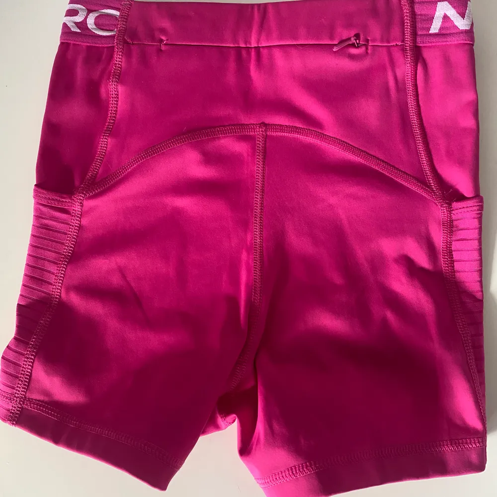 Rosa Nike pro shorts med fickor på sidorna. På baksidan av shortsen finns även en ficka med dragkedja.. Shorts.