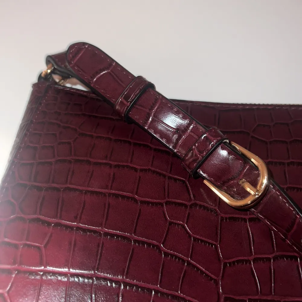 En vinröd väska i ”orm” mönster från Lindex som är i nyskick. Då den aldrig har använts.💕. Väskor.