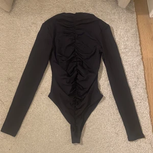 Svart bodysuit  - En jätte fin body, använd en gång, jätte bra skick, fin till fest.